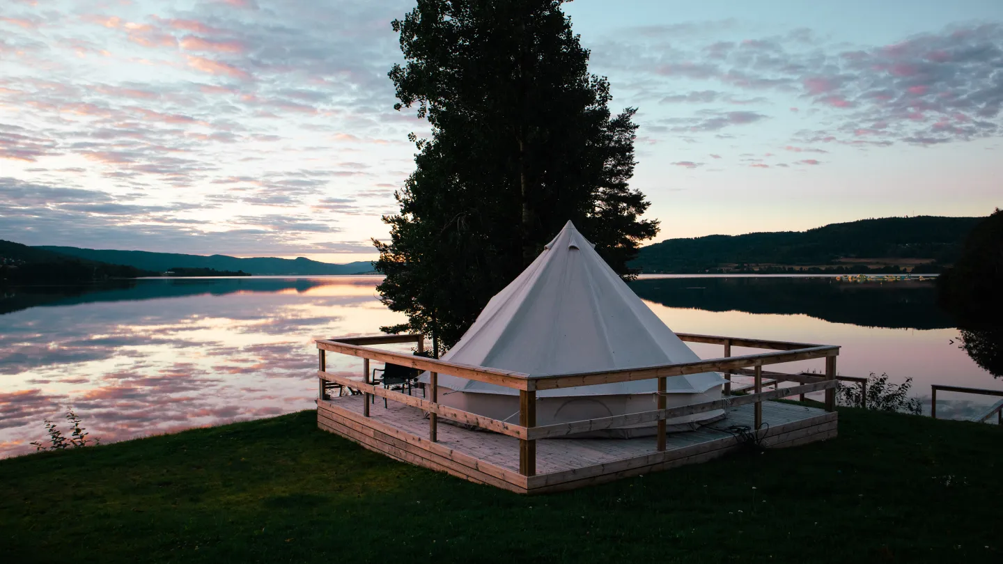 Glampingtelt under solnedgang ved Randsfjorden